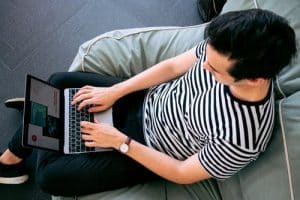 Man in stripy t-shirt-typing at laptop