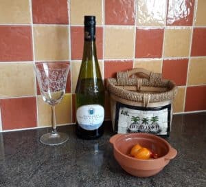 Bottle of Muscadet-wine glass-wicker garlic basket-cherry tomatoes in terracotta pot-terracotta tiles